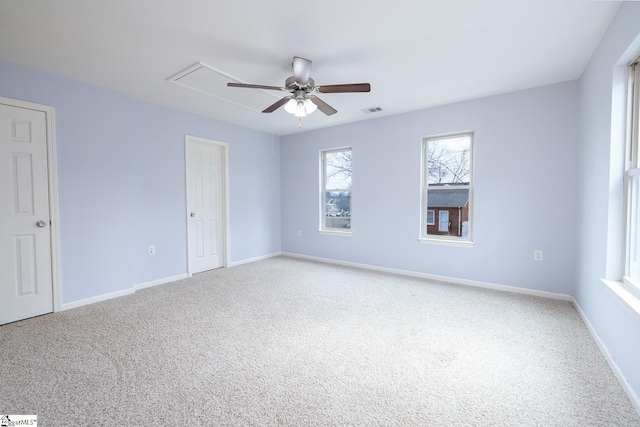 empty room featuring carpet floors, attic access, visible vents, and baseboards