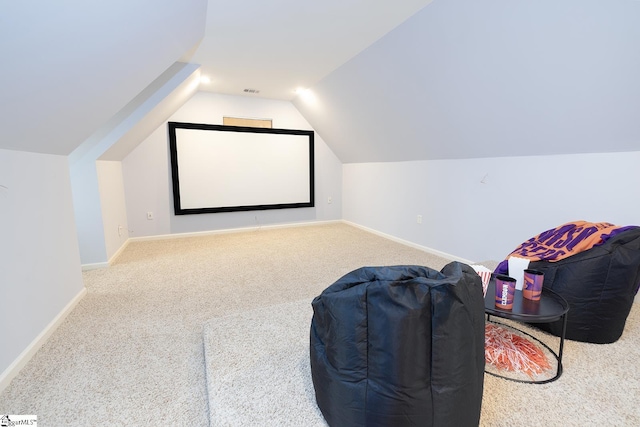 carpeted home theater room with vaulted ceiling and baseboards