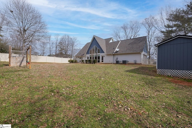 rear view of house with a lawn, cooling unit, and fence