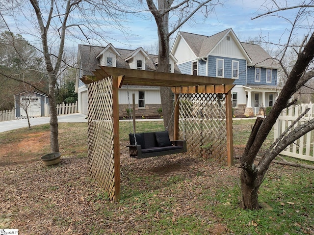 exterior space featuring a garage, stone siding, roof with shingles, and fence