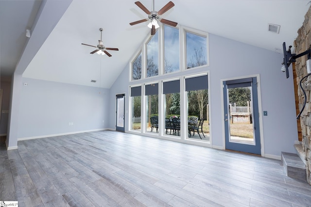 unfurnished living room with a healthy amount of sunlight, high vaulted ceiling, visible vents, and wood finished floors