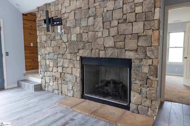 details with a fireplace, wood finished floors, visible vents, and baseboards