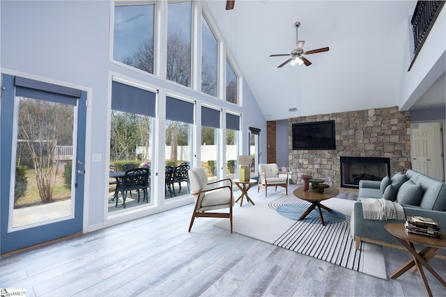 living room with ceiling fan, a fireplace, high vaulted ceiling, and wood finished floors