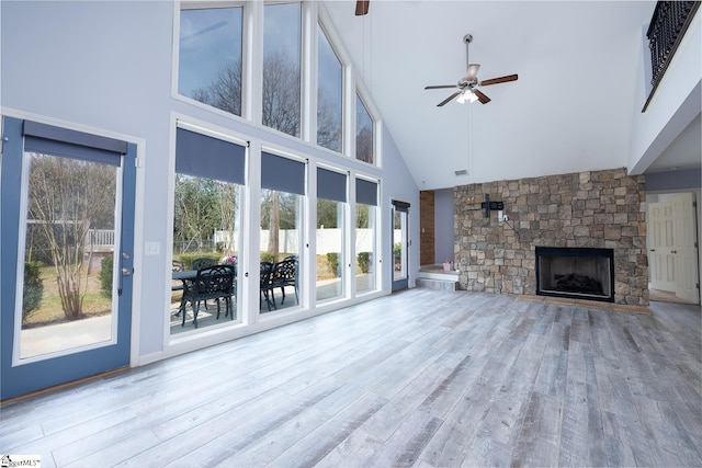 unfurnished living room with high vaulted ceiling, a fireplace, ceiling fan, and wood finished floors