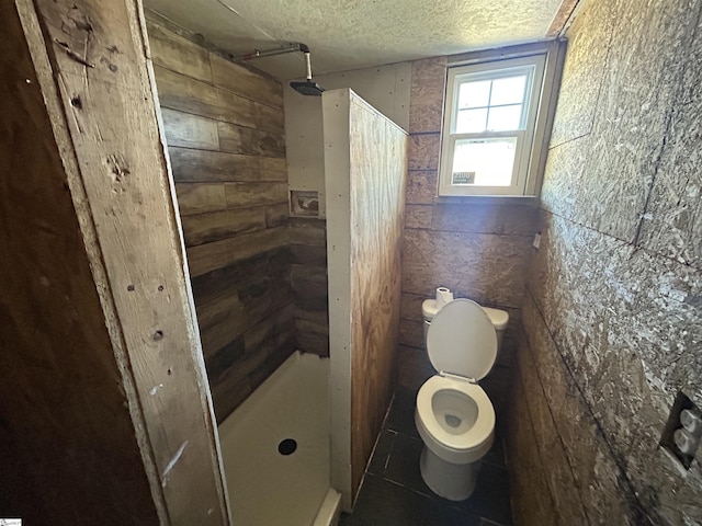 full bathroom featuring a shower stall, a textured ceiling, toilet, and tile patterned floors