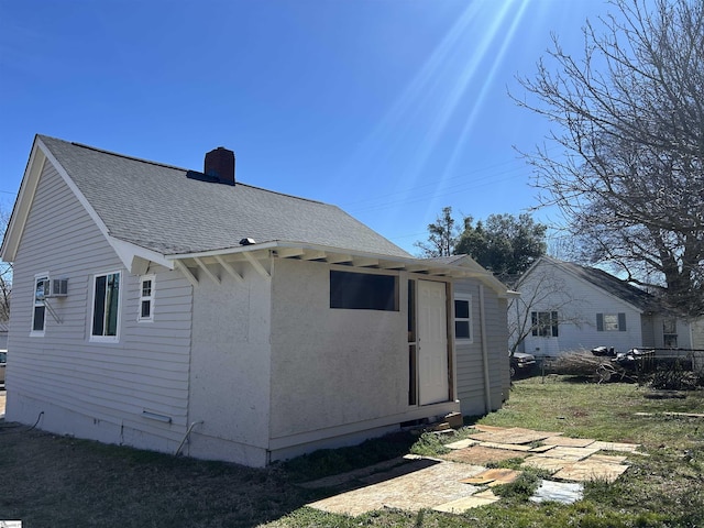 back of property with crawl space, a chimney, and roof with shingles