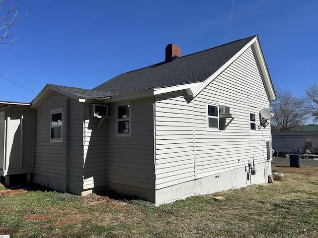 view of side of home featuring roof with shingles, a chimney, and a lawn