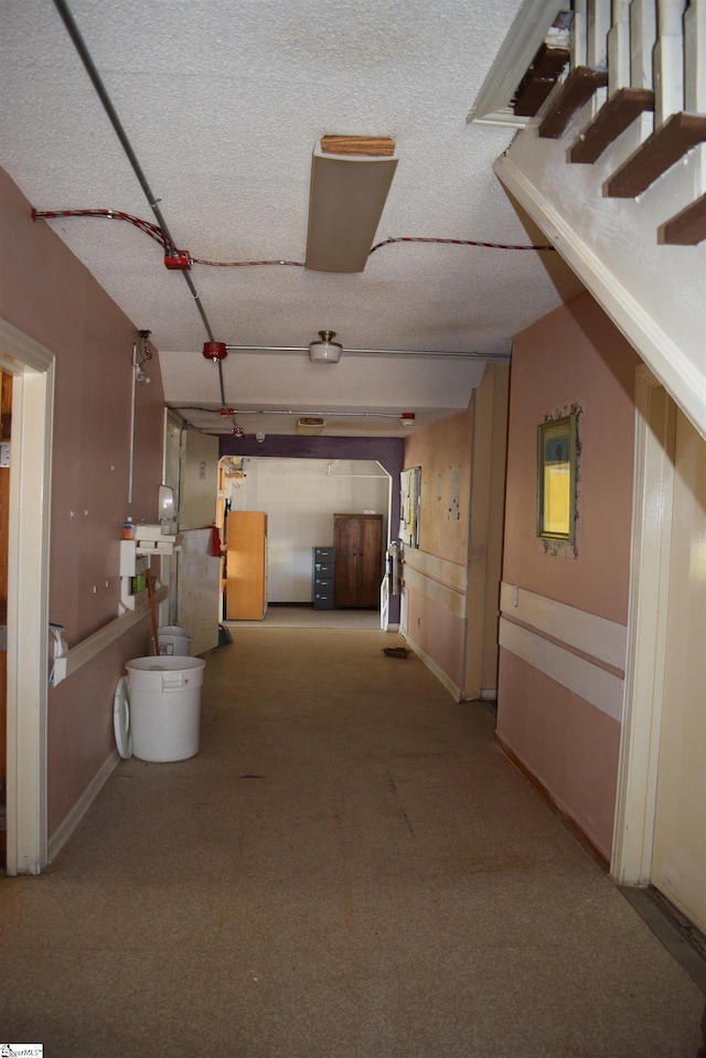 hall featuring carpet and a textured ceiling