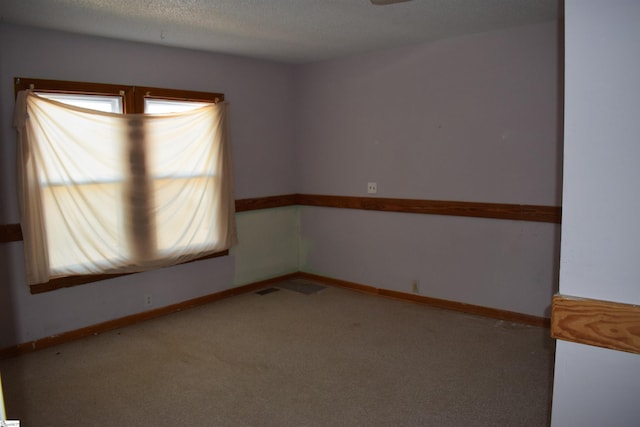 unfurnished room with carpet floors, a textured ceiling, and baseboards