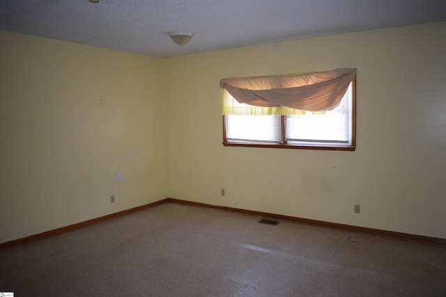 unfurnished room with carpet floors, visible vents, and baseboards