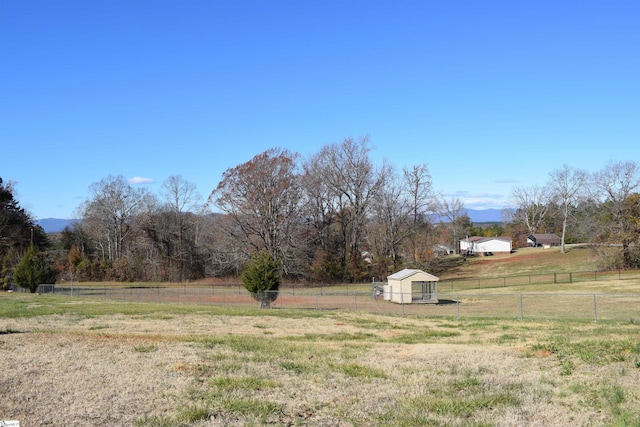 view of yard featuring fence, an outbuilding, and a rural view