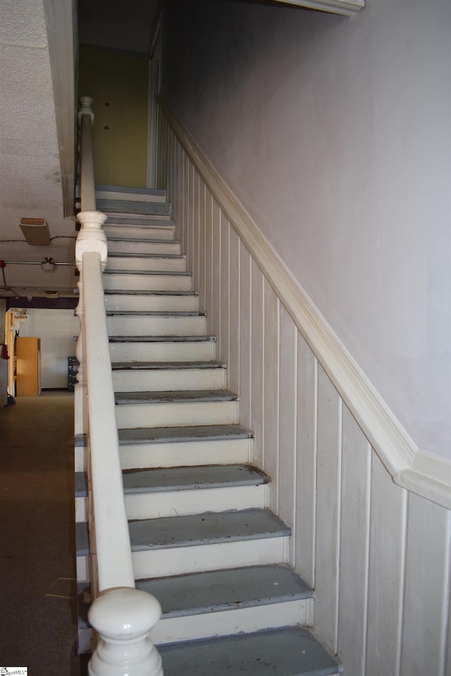 stairs with a wainscoted wall