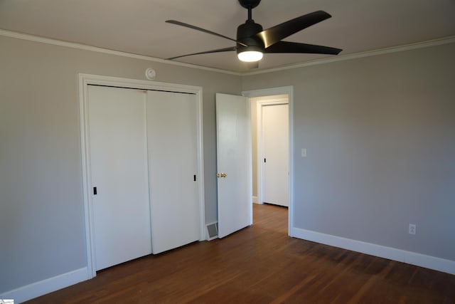 unfurnished bedroom featuring baseboards, ornamental molding, dark wood finished floors, and a closet