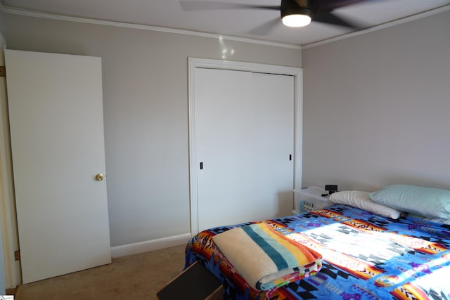 carpeted bedroom featuring ornamental molding, a closet, and ceiling fan