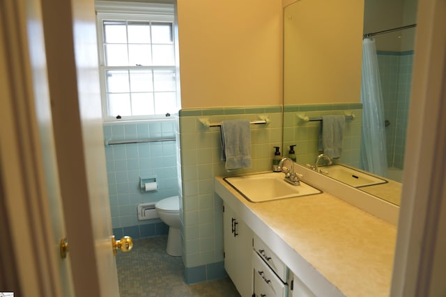 full bath featuring toilet, a wainscoted wall, vanity, tile walls, and tile patterned floors