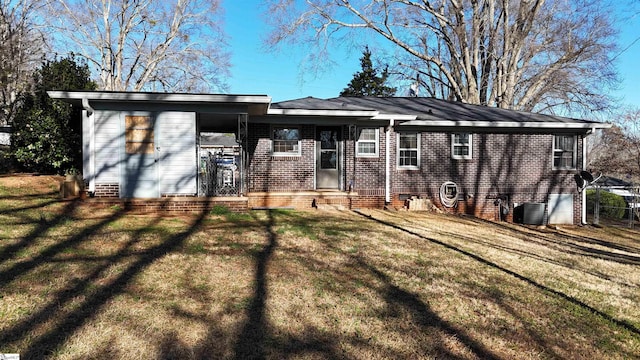 rear view of property featuring a yard, brick siding, and central AC