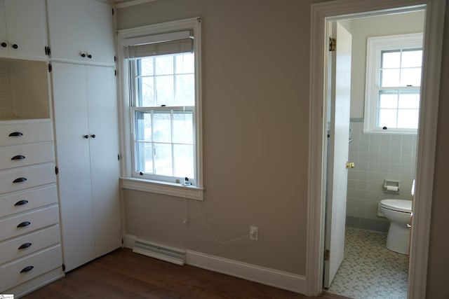 unfurnished bedroom with tile walls, a closet, visible vents, ensuite bathroom, and wainscoting