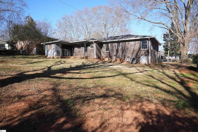 back of house with brick siding and a yard