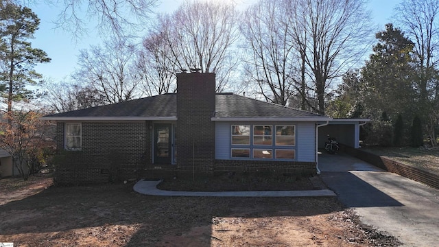 single story home featuring brick siding, driveway, a chimney, and roof with shingles