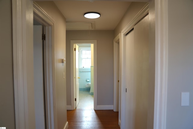 hall with dark wood-type flooring, attic access, and baseboards