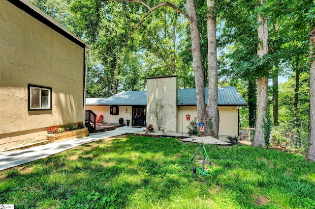 exterior space featuring a chimney, fence, a front lawn, and metal roof