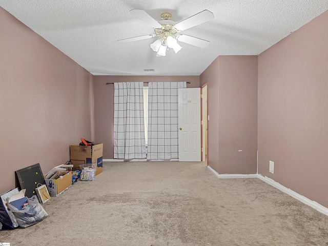 carpeted spare room with baseboards, a textured ceiling, visible vents, and a ceiling fan