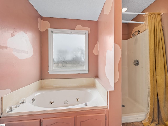 bathroom featuring a jetted tub, a textured ceiling, and a shower stall