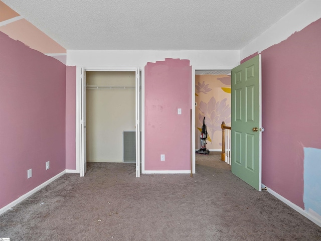 unfurnished bedroom featuring a textured ceiling, a closet, carpet flooring, and baseboards