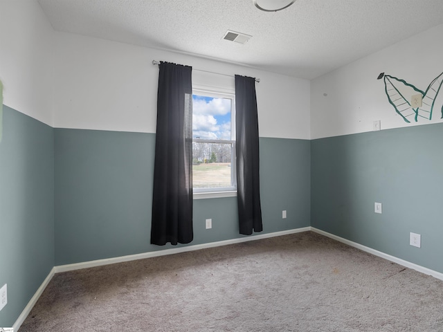 unfurnished room featuring a textured ceiling, carpet floors, visible vents, and baseboards