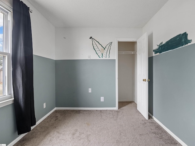 unfurnished bedroom featuring a textured ceiling, carpet flooring, and baseboards