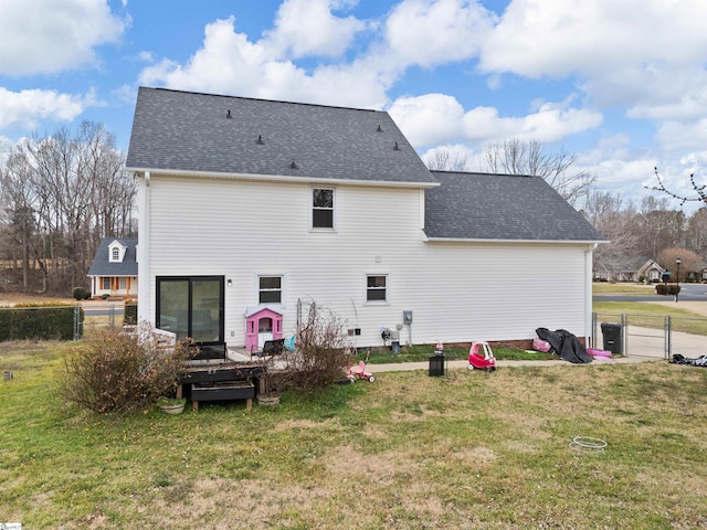 back of house featuring a shingled roof, a gate, a lawn, and fence