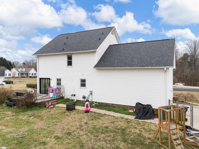 back of property with roof with shingles and a yard