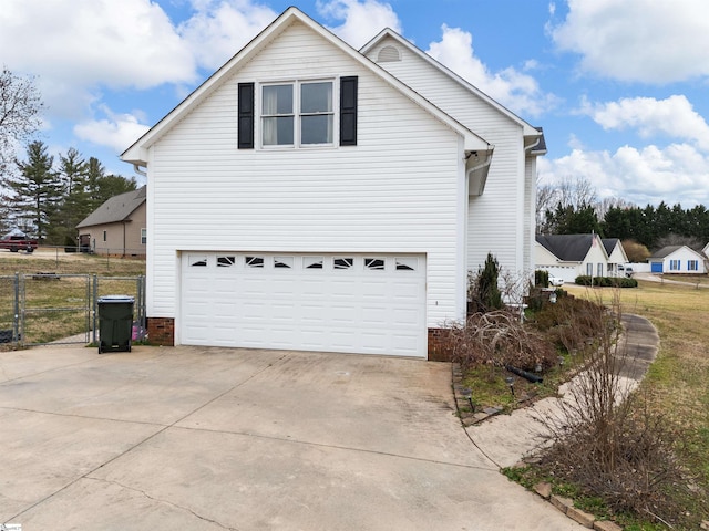 view of side of home featuring a garage, fence, and concrete driveway