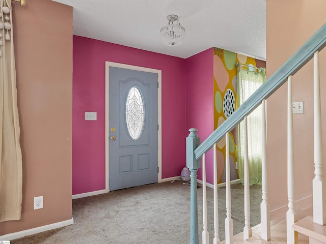 foyer entrance with a textured ceiling, stairs, baseboards, and carpet flooring