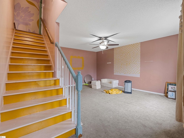 staircase featuring carpet, baseboards, ceiling fan, and a textured ceiling