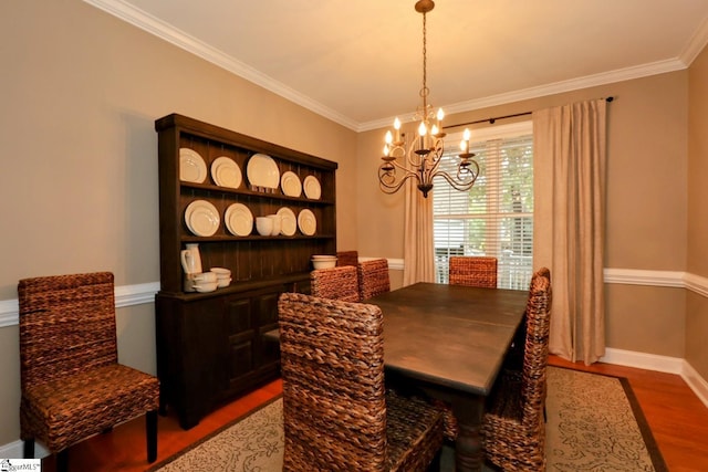 dining area with baseboards, ornamental molding, wood finished floors, and a notable chandelier