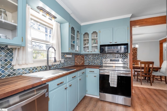 kitchen featuring crown molding, appliances with stainless steel finishes, wooden counters, and a sink