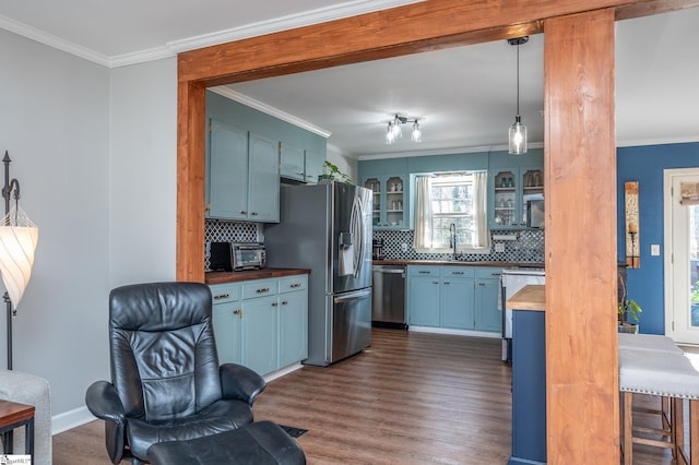 kitchen with appliances with stainless steel finishes, blue cabinetry, and crown molding