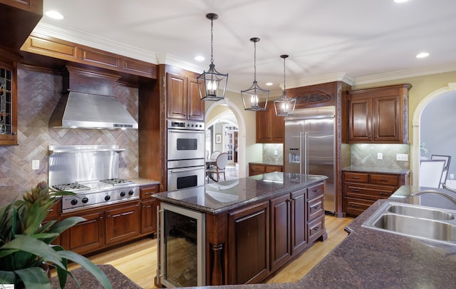 kitchen with arched walkways, beverage cooler, stainless steel appliances, a sink, and custom range hood