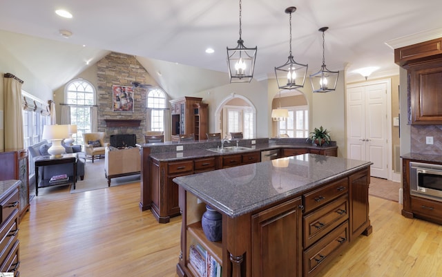 kitchen featuring a kitchen island, stainless steel appliances, light wood-style floors, a fireplace, and a sink