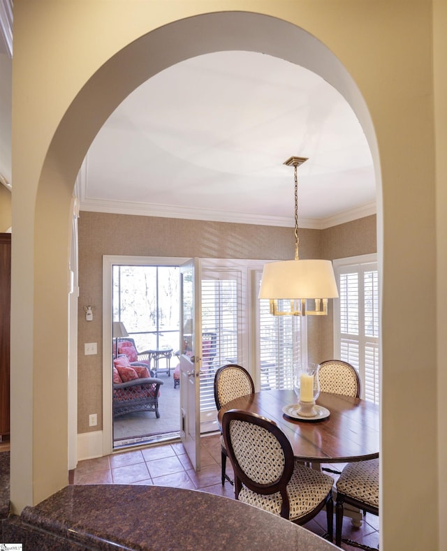 dining area featuring arched walkways, crown molding, and light tile patterned floors