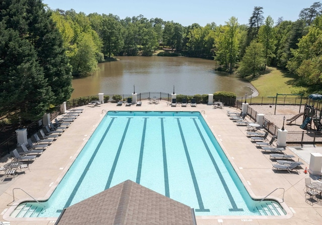 pool with a water view, a patio area, and fence