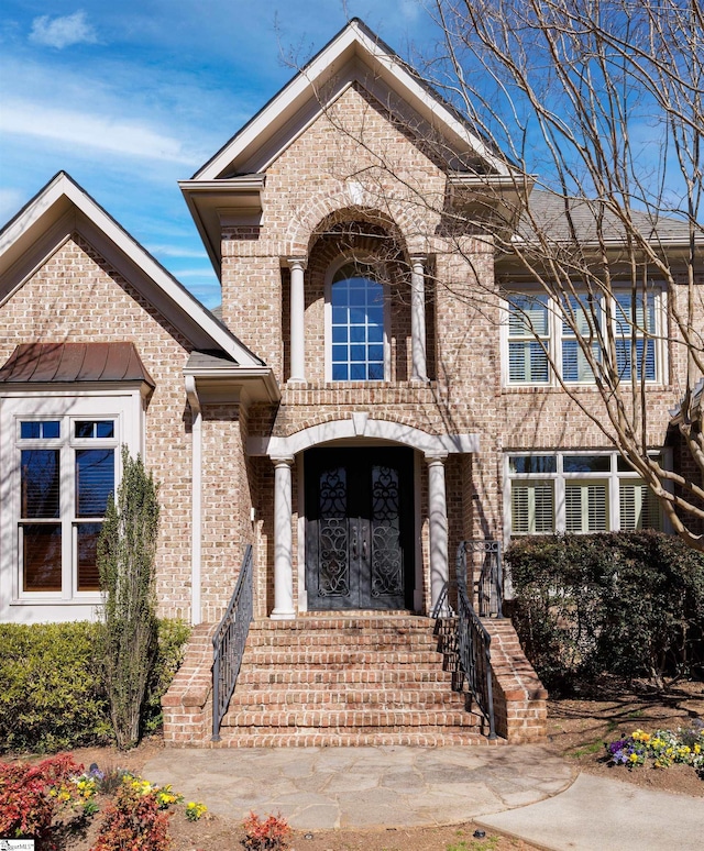 view of front facade with brick siding and a standing seam roof