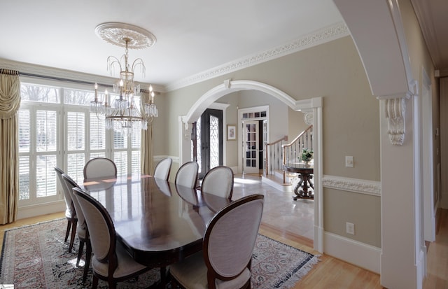 dining room featuring light wood-type flooring, a wealth of natural light, arched walkways, and stairs