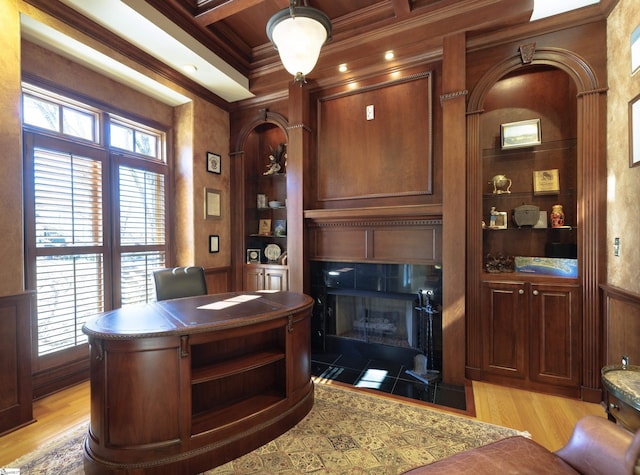 office area featuring built in shelves, a tile fireplace, light wood-style flooring, and crown molding