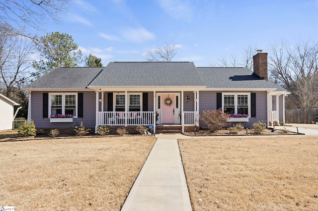 single story home featuring roof with shingles, a porch, a chimney, and a front yard