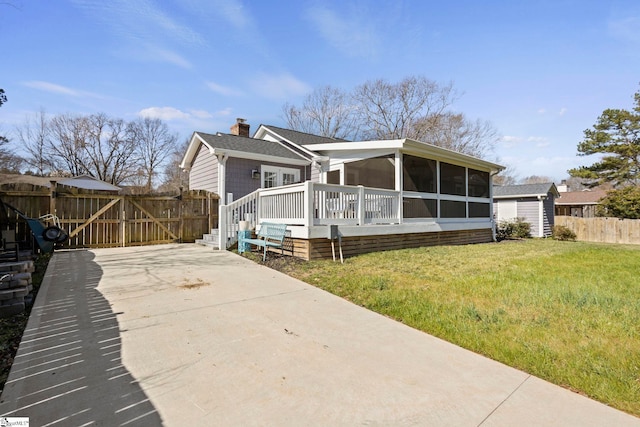 view of front facade with a sunroom, a chimney, an outbuilding, a gate, and fence