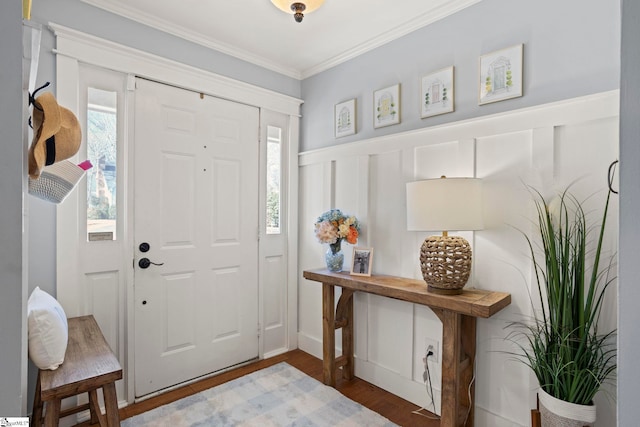 entryway with ornamental molding, wainscoting, a decorative wall, and wood finished floors