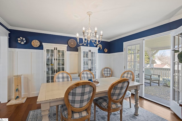 dining space with ornamental molding, wainscoting, dark wood finished floors, and a notable chandelier