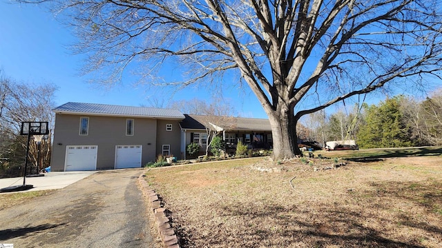 view of front of house with a garage, a front yard, metal roof, and driveway